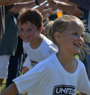 2 young boys smiling as they play soccer