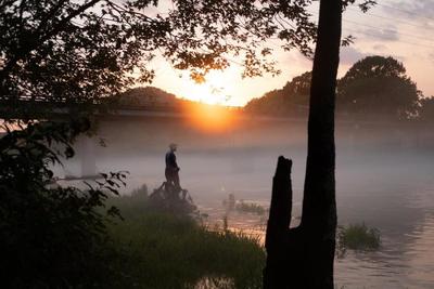 silhouette of man at lake at sunset